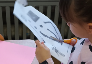 Dziewczynka siedzi i wycina części robota.