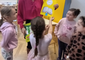 Pani stoi a dzieci wręczają jej laurkę.