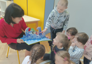 Pani czyta dzieciom bajkę i pokazuje ilustrację.