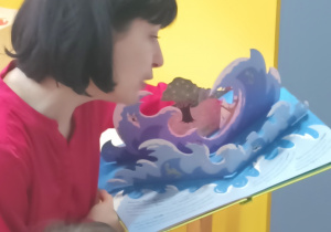 Pani czyta bajkę i pokazuje ilustrację.