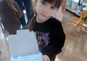 Dziewczynka pokazuje swoją pracę.