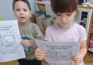 Dzieci pokazują ilustracje z kodeksu bezpiecznego korzystania z Internetu.