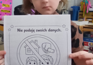 Dziewczynka pokazuje ilustracje z kodeksu bezpiecznego korzystania z Internetu.