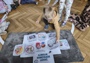 Dziecko przykleja ilustracje na plakat.