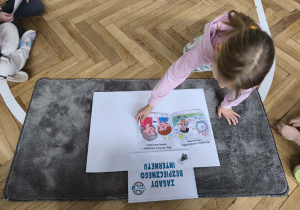 Dziecko przykleja ilustracje na plakat.