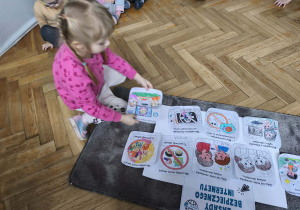 Dziecko przykleja ilustracje na plakat.