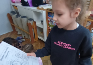 Dziewczynka pokazuje ilustracje z kodeksu bezpiecznego korzystania z Internetu.