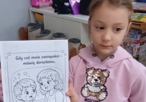 Dziewczynka pokazuje ilustracje z kodeksu bezpiecznego korzystania z Internetu.