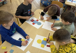 dzieci tworzą robota z figur geometrycznych