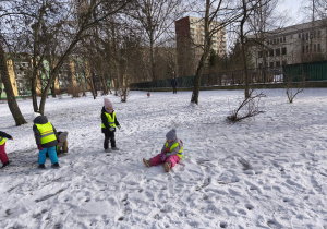 Na zdjęciu widzimy grupkę dzieci bawiących się na śniegu.