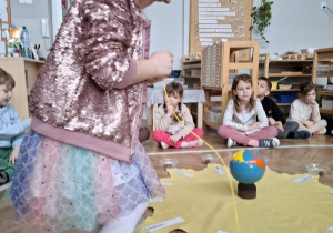 dziewczynka w różowej koronie nawleka korale na sznurek