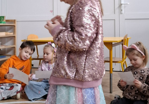 dziewczynka w różowej koronie nawleka korale na sznurek