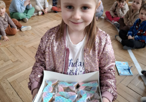 dziewczynka w rózowej koronie trzyma pudełko ze słodyczami