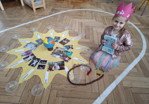 dziewczynka w różowej koronie przy słoneczku urodzinowym, w rkach trzyma laurki