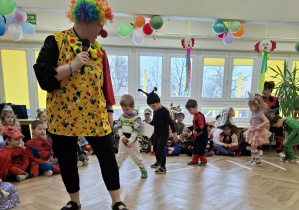 Klaun prowadzi dzieci po wyznaczonej ścieżce.