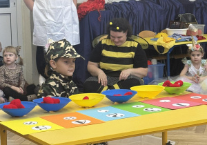 Chłopiec układa odpowiednie ilości serduszek do miseczek.