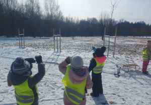 Dzieci obserwujące pojawiające się kolory podczas oglądania słońca przez sopel lodu