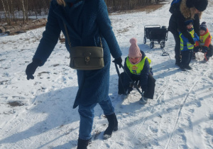 nauczyciel ciągnący dziewczynkę na sankach