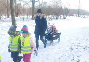 dzieci i osoba z wózkiem wchodzące do lasu