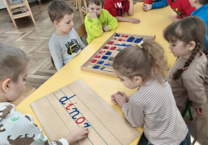 Dzieci układają słowo dinozaur z ruchomego alfabetu