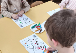 Dziecko wykleja plasteliną obrazek wesołego dinozaura
