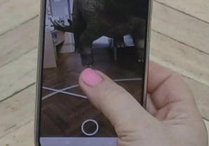 Nauczyciel pokazuje na telefonie obraz dinozaura 3d