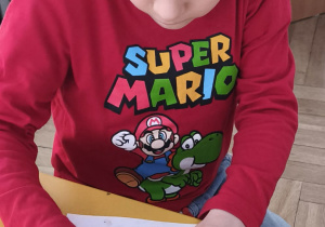 Dziecko wykleja plasteliną obrazek wesołego dinozaura