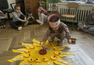Zdjęcie przedstawia dziewczynkę podczas wkładania świeczek w tort urodzinowy.