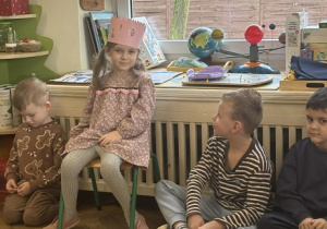 Zdjęcie przedstawia dziewczynkę podczas słuchania miłych słów od swoich kolegów i koleżanek.