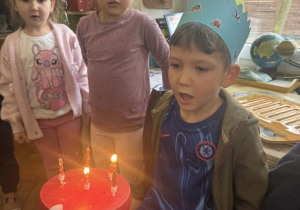 Zdjęcie przedstawia chłopca dmuchającego świeczki.