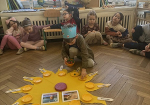 Zdjęcie przedstawia chłopca rozkładającego koraliki na słoneczku urodzinowym.