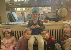 Zdjęcie przedstawia chłopca siedzącego wśród dzieci. chłopiec siedzi na krześle i ma koronę na głowie.