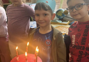 Zdjęcie przedstawia chłopca przy torcie z zapalonymi świeczkami.
