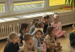 Zdjęcie przedstawia dzieci siedzące na podłodze.