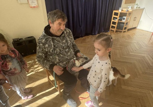 Zdjęcie przedstawia dziewczynkę głaszczącą psa.