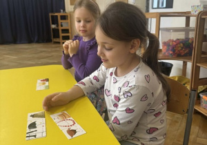 Zdjęcie przedstawia dziewczynkę układającą obrazki.