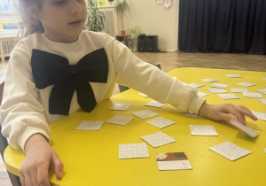 Zdjęcie przedstawia dziewczynkę odkrywającą obrazek.