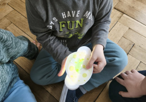 Na zdjęciach widzimy chłopca, który ogląda wnętrze jajka za pomocą lampki.