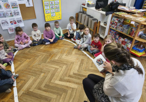 Na zdjęciu widzimy grupkę dzieci, która uważnie słucha jakiego opowiadania będziemy słuchali.