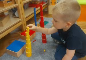 chłopiec ustawiający kolorowe cylindry