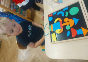 chłopiec układa obrazek z figur magnetycznych