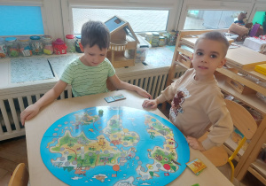 chłopcy układają mapę świata ze zwierzętami