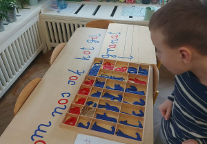 chłopiec tworzy napisy z wykorzystaniem ruchomego alfabetu