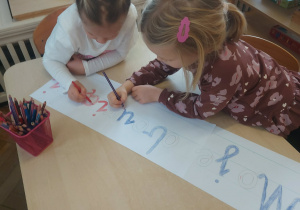 dziewczynki kolorują narysowane litery