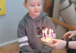 Chłopiec zdmuchuje świeczki na symbolicznym torcie.