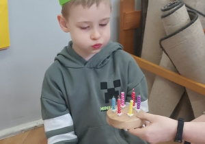 Chłopiec zdmuchuje świeczki na sybolicznym torcie.