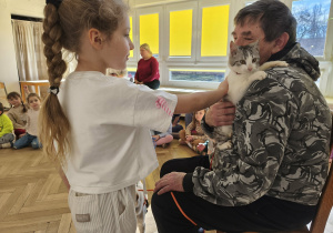 Dziewczynka głaszcze kotka.
