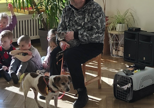 Pan siedzi na krześle a przy nim pies i kot.