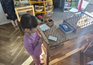 Na zdjęciu widzimy dziewczynkę, która stoi przy ilustracji przedstawiającej zakaz palenia.