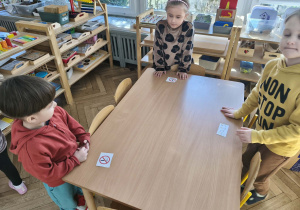 Na zdjęciu widzimy dzieci, które stoją przy ilustracjach oznaczających zakaz palenia.